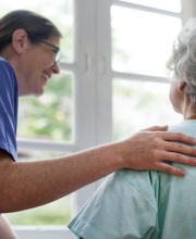 Infirmière souriante qui réalise un soin à domicile à une femme.